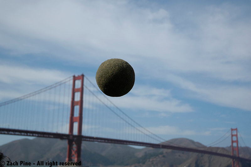 Sand Globe tossed near the Golden Gate Bridge. 2010. [Large sand globe against a cloudy blue sky, with Golden Gate Bridge and Marin mountains in background.]